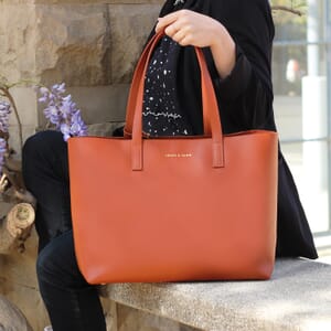 carrying view of the jules &amp; jenn brick leather tote bag